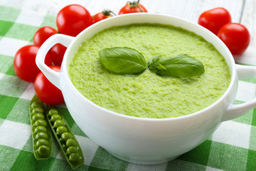 Tasty peas soup and cherry tomatoes on table close up