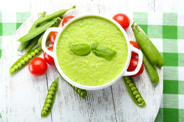 Tasty peas soup and cherry tomatoes on table close up