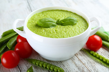 Tasty peas soup and cherry tomatoes on table close up
