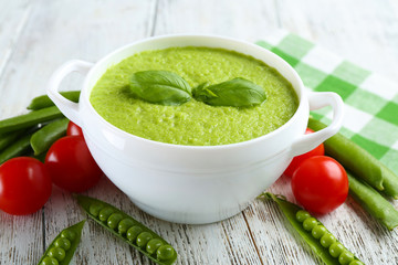 Tasty peas soup and cherry tomatoes on table close up