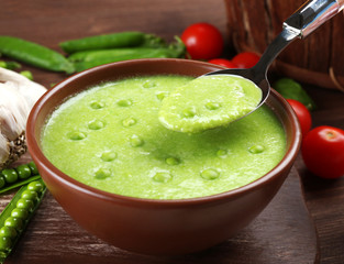 Tasty peas soup and vegetables on table close up
