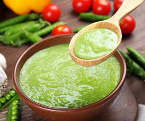 Tasty peas soup and vegetables on table close up