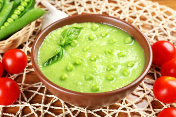 Tasty peas soup and vegetables on table close up