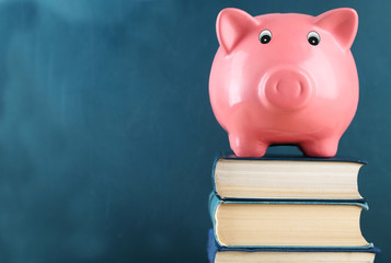 Piggy bank with books on blackboard background