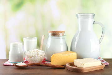 Dairy products on wooden table, on green nature background