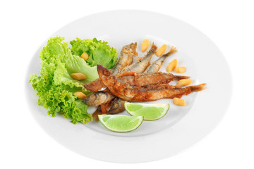 Fried small fish on plate with lettuce and lime isolated on white