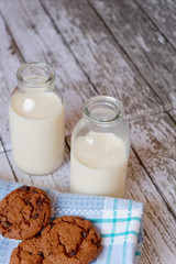 Vertical shot of some chocolate cookies and two glasses of milk on a rustic table
