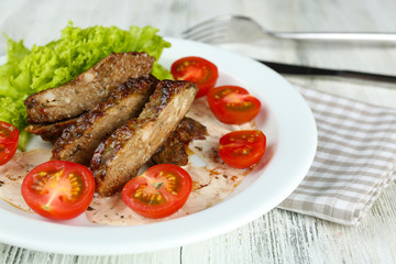 Tasty slices of meat with sauce and cherry tomato on table close up