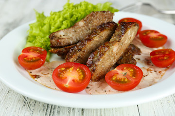 Tasty slices of meat with sauce and cherry tomato on table close up