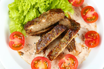 Tasty slices of meat with sauce and cherry tomato on plate close up