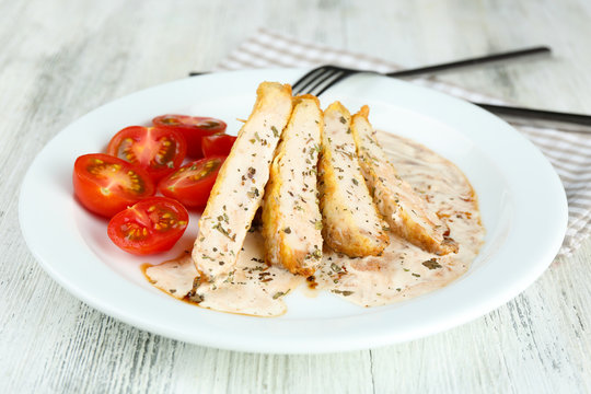Slices of chicken fillet with spices and cherry tomato on table close up