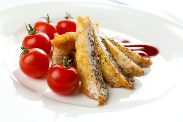 Slices of chicken fillet with sauce and cherry tomato on plate close up