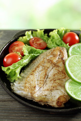 Dish of fish fillet with salad and lime on bright background