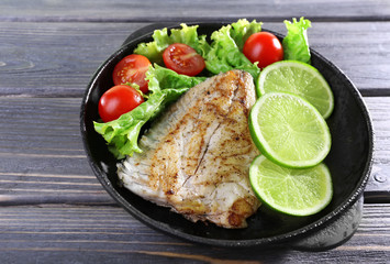 Dish of fish fillet with salad and lime on table close up