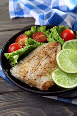 Dish of fish fillet with salad and lime on table close up