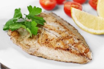 Dish of fish fillet with parsley and lemon on plate close up