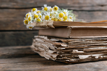 Old books with dry flowers on wooden background