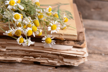 Old books with dry flowers on table close up