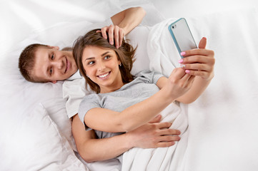 Couple in bed taking a picture with smartphone