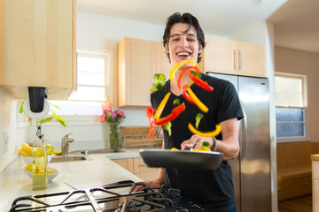 Cook handsome chef man flips tosses veggies on frying pan making dinner
