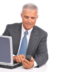 Businessman Dialing Cell Phone Seated at Computer