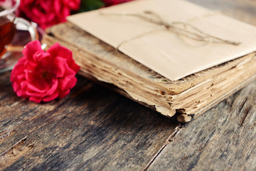 Old book with beautiful flowers on wooden table close up