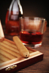 Cigars in humidor with cognac on wooden table, closeup