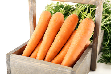 Young carrots in wooden box isolated on white