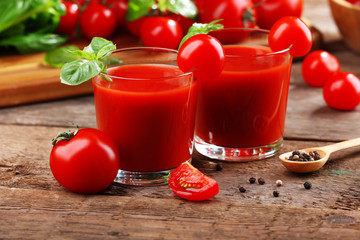Glasses of tomato juice on wooden table, closeup