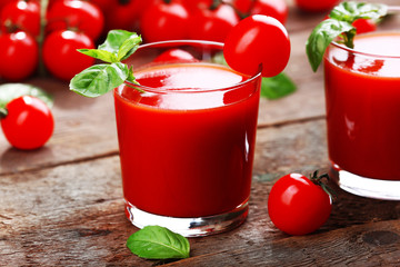 Glasses of tomato juice on wooden table, closeup