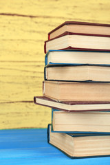 Stack of books on yellow wooden background