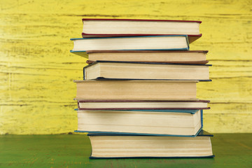 Stack of books on yellow wooden background
