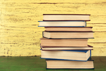 Stack of books on yellow wooden background