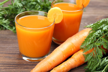 Glasses of carrot juice with vegetables on table close up