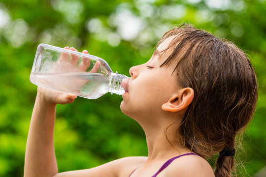 Child drinking clean tap water from transparent plastic bottle