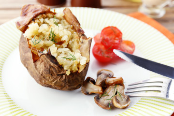 Baked potato with cheese and mushrooms on plate close up