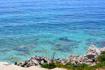 Fototapeta na wymiar Rocky beach with clear blue water on a sunny day