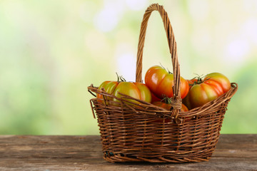 Green tomatoes in basket on bright background