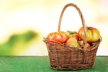 Green tomatoes in basket on bright background