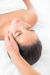 Fototapeta na wymiar Attractive young woman receiving facial massage at spa center