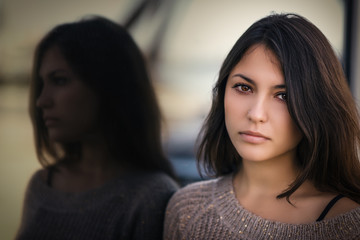 Portrait of a beautiful brunette. Reflection in the mirror. Selective focus. Color toned image.