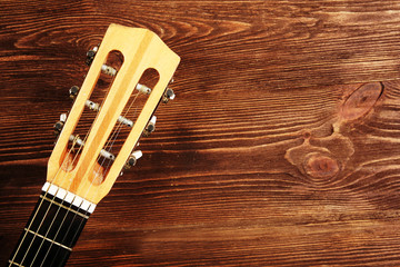 Neck of acoustic guitar on wooden background