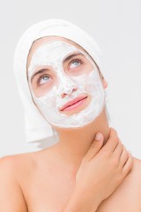 Thoughtful woman having white cream on her face 