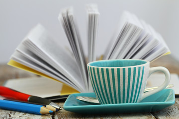 Cup of coffee with open book in the background
