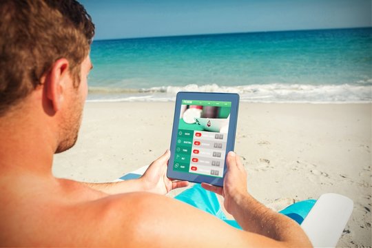 Composite image of man using digital tablet on deck chair