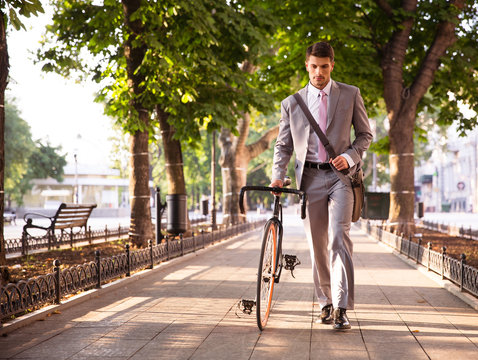 Pensive businessman walking with bicycle