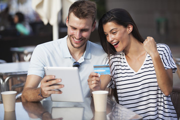 Couple buying online on holidays with a tablet and credit card on terrace bar