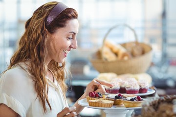 Astonished pretty woman pointing at cakes
