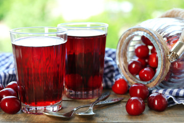 Glasses of sweet homemade cherry compote on table on bright background