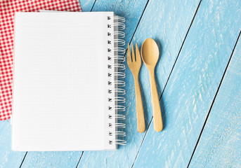 Notebook with wooden spoon on wood table